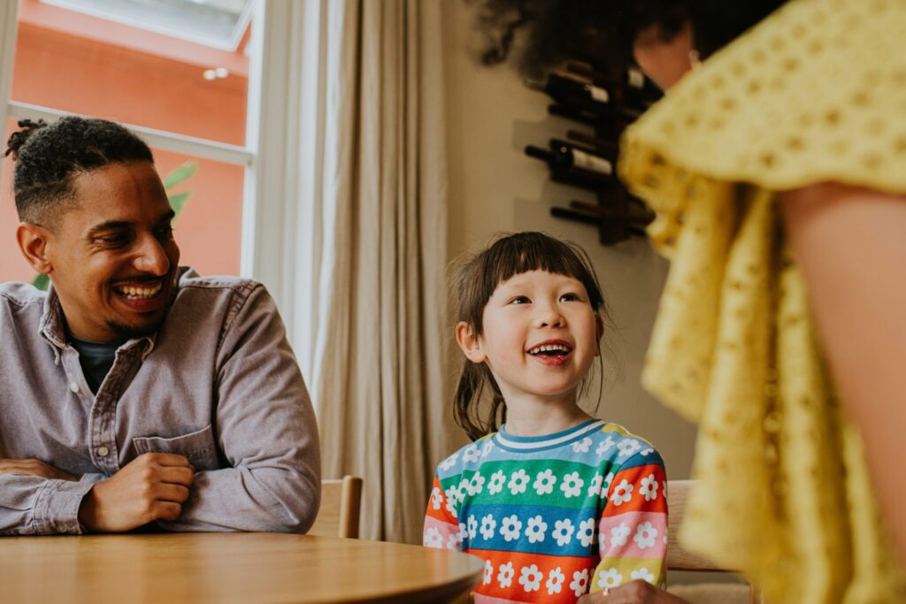 a young girl smiles while sitting at a table with her foster parent